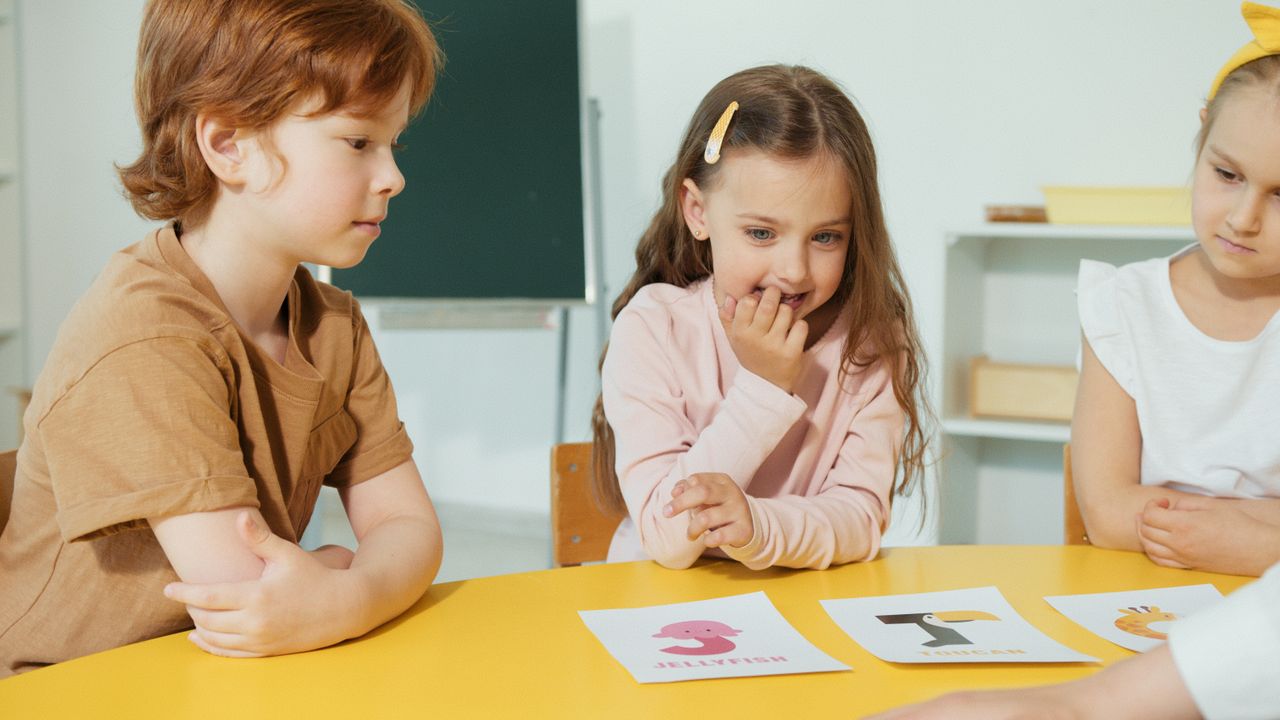 Mastering the First Impression: Your intriguing post title goes here Group of kids engaging in a classroom activity with educational cards on a yellow table.